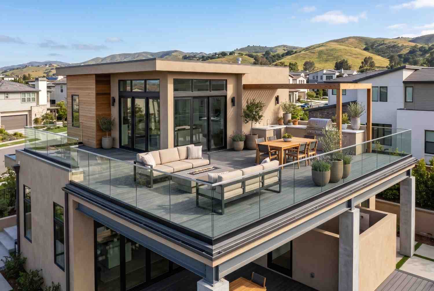 Modern luxury home featuring a rooftop deck with glass railings, outdoor kitchen, and lounge area, showcasing custom home design, rooftop outdoor living space, contemporary architecture, residential construction, and premium real estate development with scenic hillside views